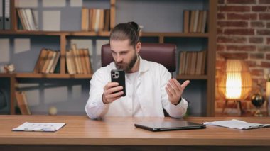 Kafası karışmış Kafkasyalı bir adam akıllı telefon tutuyor ve avuç içi açık el hareketi yapıyor. Arama sırasında bir şeyi sorgulamak ya da beklenmedik bir mesaja tepki vermek. Çevrimiçi kişiden açıklama ya da netlik aranıyor.