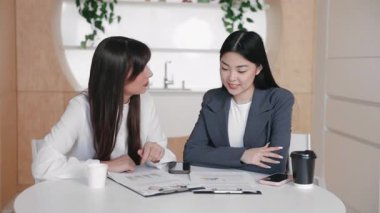 İş arkadaşları, ofis ortamında gülümseyen grafikleri tartışırken belgelerin üzerine eğildiler. Fikirler için beyin fırtınası yapmak ya da performans hedeflerini tartışmak. Akıllı telefonlar ve kahve fincanları masada..