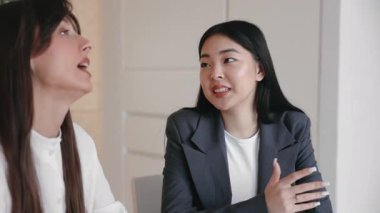 Sessiz çalışma alanında meslektaşının yanında otururken düşünceli bir şekilde konuşan sakin genç bir profesyonel. İşbirlikçi toplantı sırasında perspektif paylaşımı ya da açıklama fikri ya da günlük tartışma.