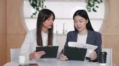 İş ortakları masadaki yorumları paylaşırken panolardaki çizelgeleri karşılaştırıyorlar. İlerleme raporlarının gözden geçirilmesi veya sunumdan önce sabah brifinginde kilit rakamların hizalanması.