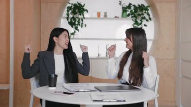 İki hevesli kadın birlikte dizüstü bilgisayar kapattıktan sonra tezahürat yapıyor. Parlak yaratıcı çalışma alanında heyecanı ifade ederken başarıyı veya başarılı buluşmayı kutlamak.