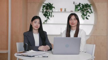 İki bayan yönetici sakince dizüstü bilgisayarın arkasında oturuyor ellerinde evrak işleri ve masada kahveyle. Doğrudan kameraya bakıyorum. Şirket iletisi kaydediliyor ya da sanal müşteri toplantısına hazırlanılıyor.