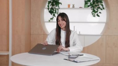 Samimi ışık odasında yuvarlak masada oturan neşeli beyaz kadın başarıyı kutluyor. Görevi tamamladıktan ve bilgisayarı kapattıktan sonra yumruklarını kaldırıp gülümsüyorsun. Gururlu ve heyecanlı.