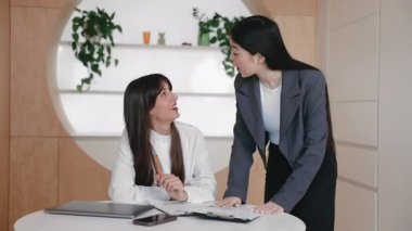 Mutlu melez kadınlar takım çalışması başarısını masanın yanında dururken beşlikle kutluyor. Panodan olumlu sonuçlar almak için. İş büyümesini gözden geçirdikten sonra heyecanı ifade etmek.