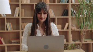 İçeriği beyaz bir kadın ekranda bir şey okurken hafifçe gülümsüyor. Hoş bir ileti gözden geçiriliyor veya çevrimiçi oturum sırasında arkadaşça geri bildirimleri kontrol ediliyor ve sessizce tatmin ediliyor.