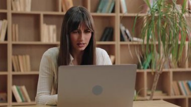 Düşünceli, beyaz bir kadının dizüstü bilgisayara bakarken başını eğmesi. Çevrimiçi görev sırasında hatanın farkına varılması, programdaki hatanın farkına varılmasının ardından başını hafifçe sallaması.