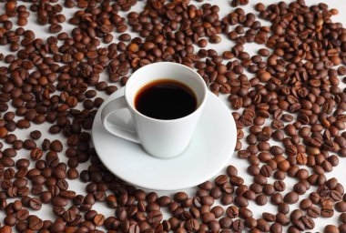 Beyaz arka planda kavrulmuş fasulyeli siyah espresso kahvesi konfor, aroma ve sabah enerjisinin özünü yakalar.