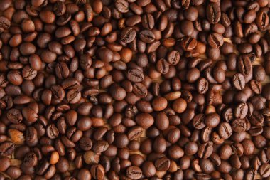 Koyu kavrulmuş kahve çekirdeklerinin tepeden tırnağa perspektifi zengin renklerini ve parlak parıltılarını vurgulayarak kaliteli kahvenin özünü yakalıyor.