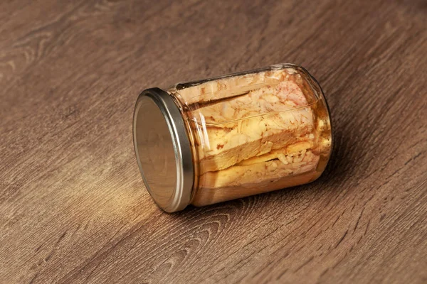 保存在玻璃瓶中的金枪鱼片 隔离在木制的背景上 — 图库照片