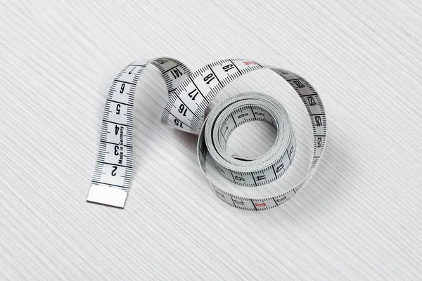 Measuring tape isolated on a white wooden background