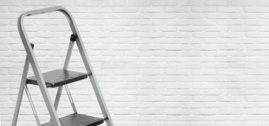 Beyaz tuğla duvar zemininde alüminyum merdiven