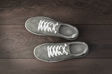 Deri gri erkek ayakkabıları beyaz dantelli ve kauçuk tabanlı ahşap kahverengi zemin üzerinde. Erkek spor ayakkabıları. Modaya uygun spor ayakkabılar. Erkek modası, hipster ayakkabıları.