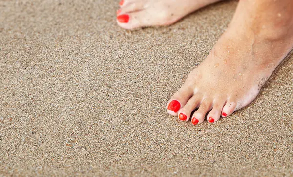 在沙滩上的沙地上有修脚的女人的脚靠得很近 免版税图库照片