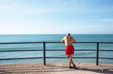 Bir adam denize bakıyor.