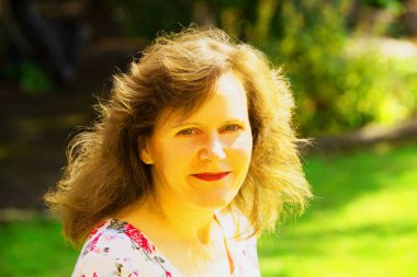 Çekici bir esmer ve düşünceli bir bayanı sabahın erken saatlerinde bahçesinin ön planında güneşli bir anın tadını çıkarırken yakalıyor..