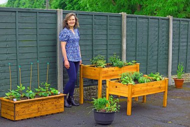 Mutlu ve çekici bir kadın bahçıvan, Mayıs 'ın sonlarında yaz ekimi hazırlıklarını gururla gösterir..