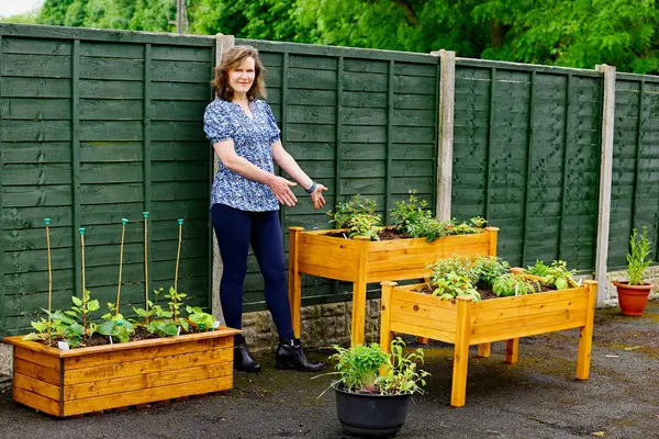 stock image A happy and attractive female gardener, proudly shows off her summer planting preparations in late May.