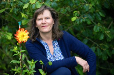 Çekici, sağlıklı ve zinde bir kadın bahçıvan yeni bir yaz çiçeği ekiyor..