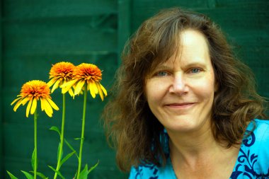 Haziran 'da Doncaster' da sağlıklı ve gelişmekte olan bir Echinacea çiçeği seti yanında olgun ve mutlu bir esmer kadın yakalamak..