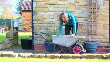 Çekici bir kadının baharın başlangıcında gübreleme ve bahçe tencerelerini tazelemeye başlaması..