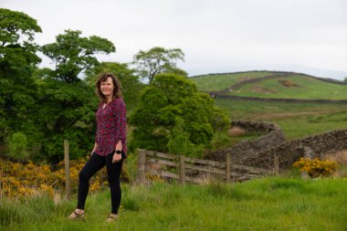 Çekici ve mutlu bir bayanı, kamp hazırlıklarını tamamlamak üzere Skipton, North Yorkshire, İngiltere 'deki Draughton Heights' ın muhteşem manzarasının tadını çıkarmak için yakalıyorum..