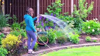 Çağdaş giysiler içindeki çekici bir bayanı yakalamak, yaz çiçeklerini sulamak..