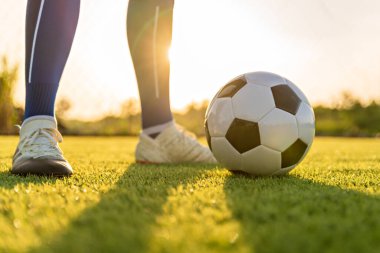 Güneş doğarken futbol sahasında topla ayakta duran bir sporcu, arka planda futbol topu, top hareketi, futbol kulübünde popüler sporlar..