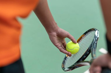 Erkek tenis topu ve tenis raketi oynar, profesyonel tenis oyuncusu, spor ve sağlıklı yaşam tarzı, açık hava sporları, raket ve yeşil top konsepti.