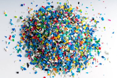 Ezilmiş küçük plastik parçaları. Geri dönüşüm için ezilmiş şişe kapakları. Plastik atıkla plastik kenar karışacak. Plastiği küçültme kavramı.