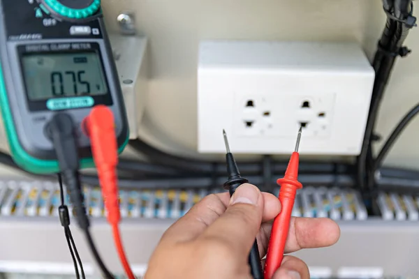 Electrician use dijital clamp meter for repair electrical equipment. Energy concept. electric wire circuit. Check Voltage before starting work. Safety first.