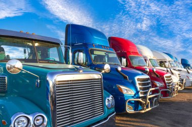 Bir otoparkta ticari kargo taşıyan uzun mesafeli konteynır kamyonları teslimata hazır..