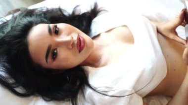 Mutlu Asyalı Genç Kadın Modeli Yatakta Yatıyor ve Kamera 4k 'ye Gülümsüyor