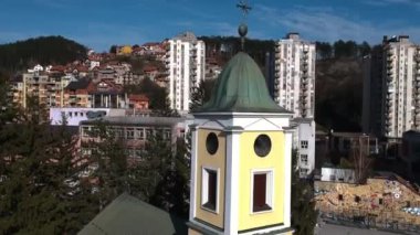 Uzice, Serbia. Aerial View of Orthodox Church in Downtown, Residential Buildings and Kids Playing on Basketball Court, Pedestal Drone Shot