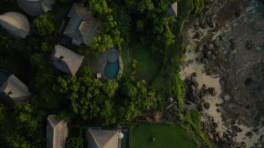 Bali, Endonezya. Sahildeki ve okyanustaki uçurumlardaki Villas 'ın tepeden aşağı hava manzarası. Yüksek Açı Drone 4K