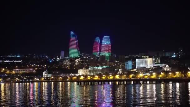 夜のバクアゼルバイジャンの炎の塔 ランドマーク建物の国旗アニメーションとカスピ海の水への反射4K — ストック動画