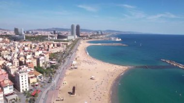 Barceloneta Sahili, Barselona, İspanya. Sunny Day 4K 'de Sandy Shore, Gezinti Alanı ve Rıhtım Binalarının Hava Görüntüsü