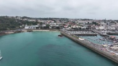 St. Peter limanı, rıhtım ve sahil binalarının havadan görüntüsü, Guernsey, Channel Adaları 4k