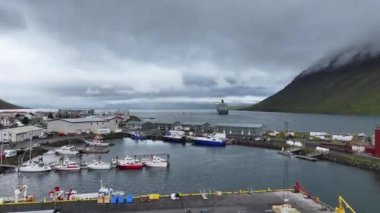 İzlanda, Isafjordur. Bulutlu Gün 60fps 'ta Liman ve Fiyorttan Giden Seyir Gemisinin İHA Çekimi