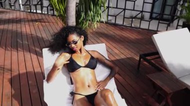 Siyah bikinili seksi Latin Kadınlar Sunbed 'de güneşleniyor.