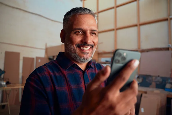 Багаторасовий Чоловік Середнього Віку Посміхається Тримаючи Мобільний Телефон Деревообробній Фабриці — стокове фото