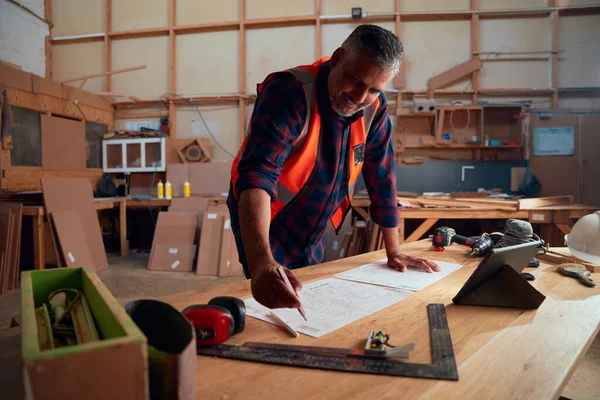 木工工場の工具と木材の間の紙に書く多人種の中間大人の男性 — ストック写真
