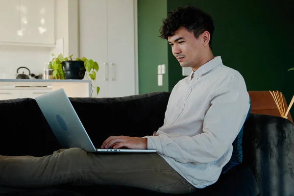 Νεαρός Πολυφυλετικός Άνδρας Πουκάμισο Που Χρησιμοποιεί Φορητό Υπολογιστή Ενώ Κάθεται — Φωτογραφία Αρχείου