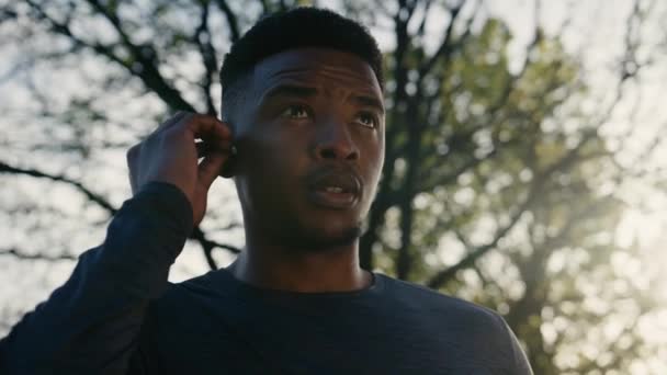 Młody Czarny Mężczyzna Bezprzewodowych Słuchawkach Wydychając Skacząc Podczas Rozgrzewki Biegania — Wideo stockowe