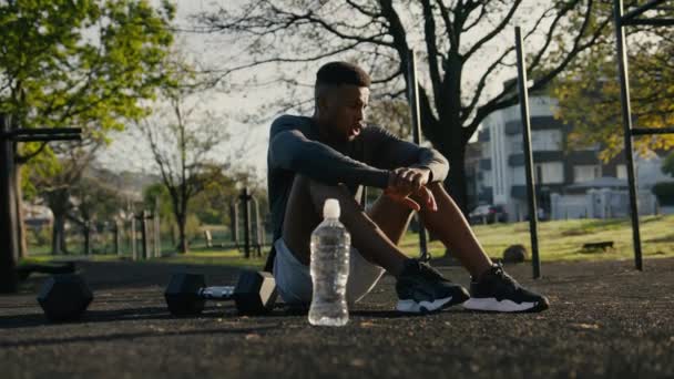 Молодой Черный Мужчина Спортивной Одежде Отдыхает Пользуется Мобильным Телефоном Тротуаре — стоковое видео