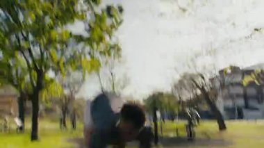 Spor kıyafetli genç siyah adam parkta spor yaparken hızla geğiriyor.