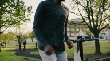 Spor giyimli genç bir adam parkta yoğun dizleriyle kardiyovasküler egzersiz yapıyor.