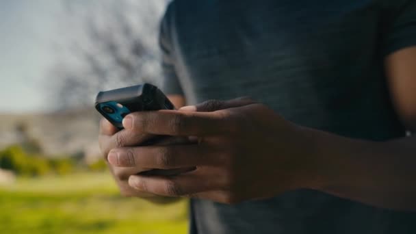 Крупним Планом Молодий Чорний Чоловік Друкує Мобільному Телефоні Посміхається Під — стокове відео