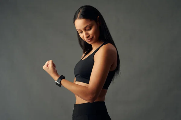 Jovem Mulher Biracial Vestindo Rastreador Fitness Flexionando Músculos Bíceps Estúdio — Fotografia de Stock