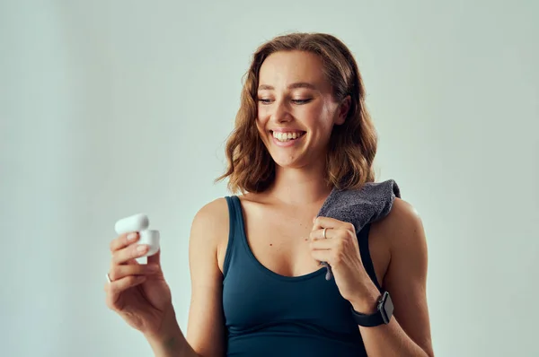 Mujer Caucásica Joven Con Sujetador Deportivo Sonriendo Mientras Sostiene Auriculares —  Fotos de Stock