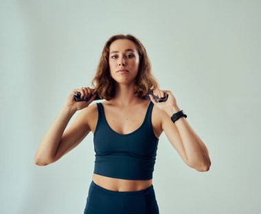 Three quarter length portrait of focused young caucasian woman wearing sportswear with towel around neck